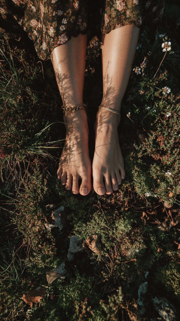 Bare feet in sunlight standing on greenery with shadows and wildflowers. Nature connection and relaxation concept.