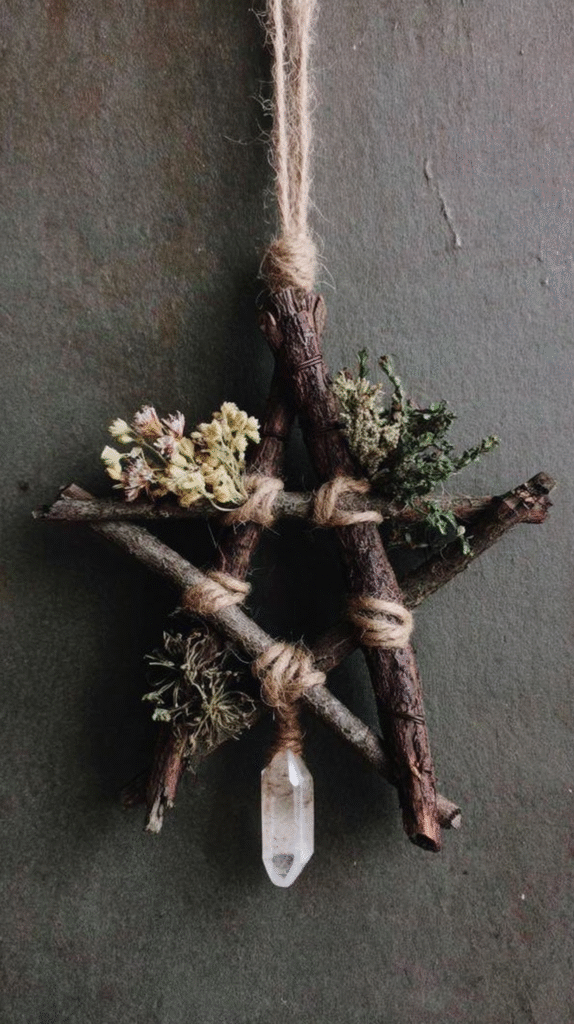 Handmade rustic star with twine, branches, dried flowers, and crystal hanging against a textured background.