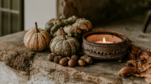 Rustic fall decor with mini pumpkins, acorns and a lit candle on a stone mantel, cozy autumn farmhouse scene