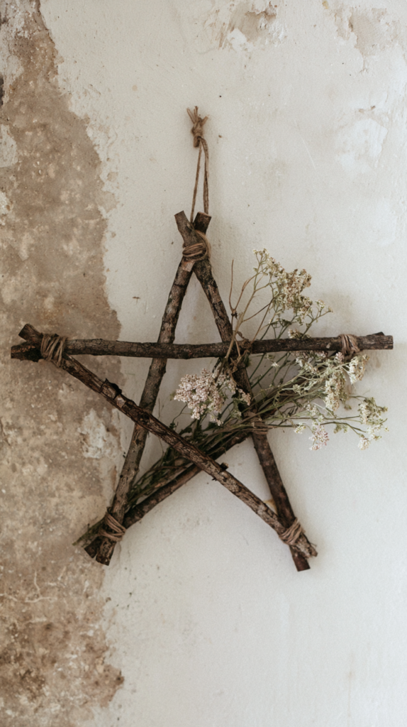samhain-nature-crafts-star Rustic twig star wreath wall hanging with dried wildflowers and twine on textured plaster wall, farmhouse decor.