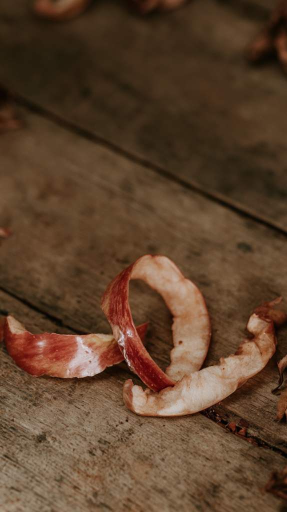 Close-up of curled apple peels on a rustic wooden table, food waste for compost or fall baking prep